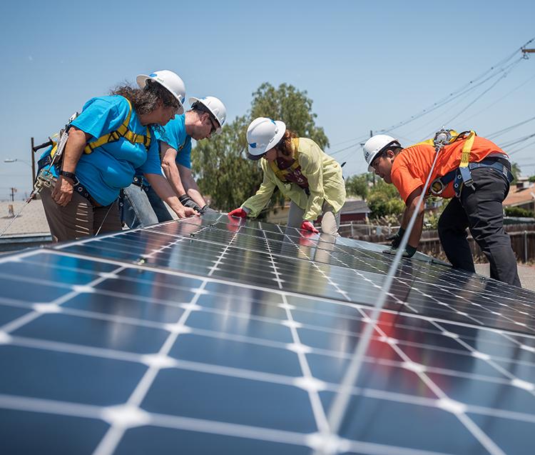 西班牙&E team members install solar panels