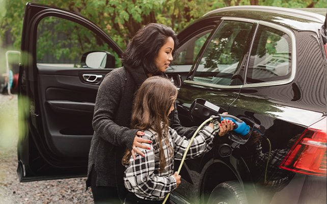 A mother and child charging their electric vehicle at an EV station